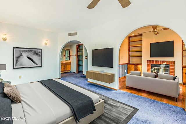 bedroom featuring a brick fireplace and ceiling fan