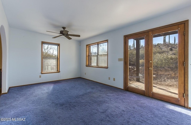 empty room featuring french doors, ceiling fan, and dark colored carpet