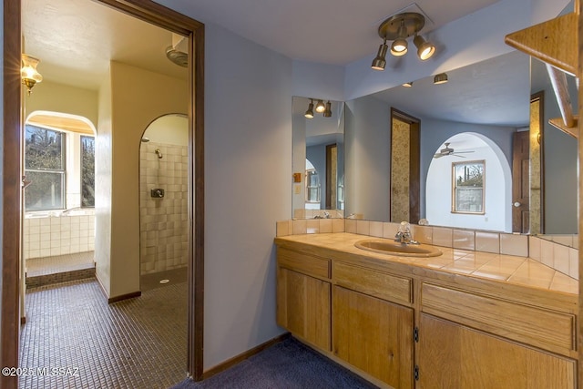 bathroom with a tile shower and vanity