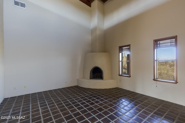 unfurnished living room featuring a towering ceiling and a fireplace