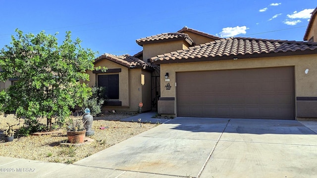 mediterranean / spanish-style house featuring an attached garage, driveway, a tiled roof, and stucco siding