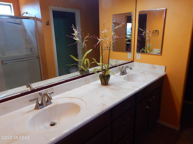 bathroom featuring an enclosed shower, a sink, and double vanity