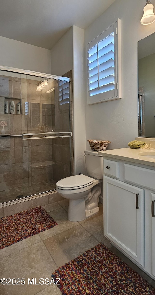 bathroom with vanity, a shower with door, and toilet