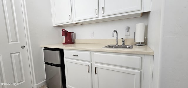 kitchen featuring sink, white cabinets, and stainless steel refrigerator