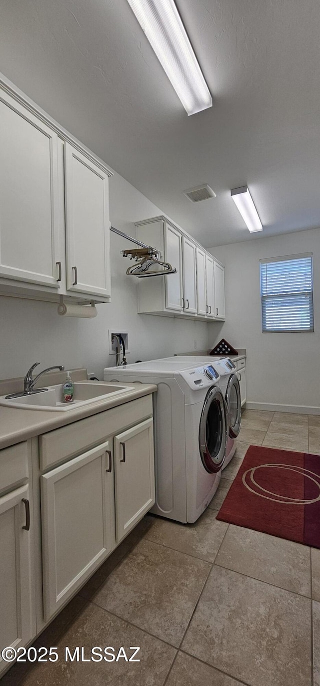 clothes washing area with cabinets, sink, washer and dryer, and light tile patterned floors