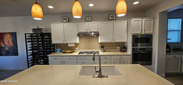 kitchen with decorative light fixtures, white cabinetry, sink, decorative backsplash, and stainless steel appliances