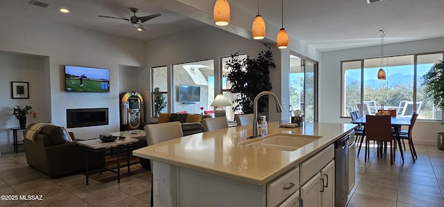 kitchen featuring sink, white cabinetry, decorative light fixtures, dishwasher, and an island with sink