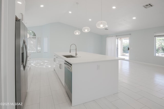 kitchen featuring sink, stainless steel appliances, an island with sink, white cabinets, and decorative light fixtures