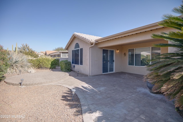 rear view of house featuring a patio area and stucco siding