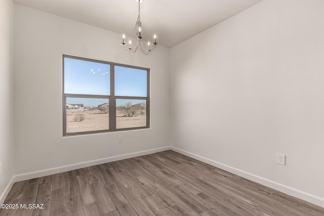 spare room featuring hardwood / wood-style flooring and a chandelier