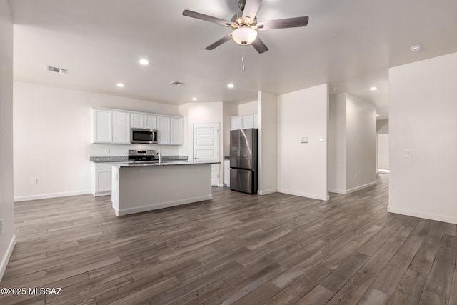 kitchen with white cabinetry, an island with sink, dark hardwood / wood-style flooring, ceiling fan, and stainless steel appliances