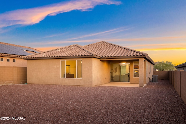 back house at dusk with a patio and central AC