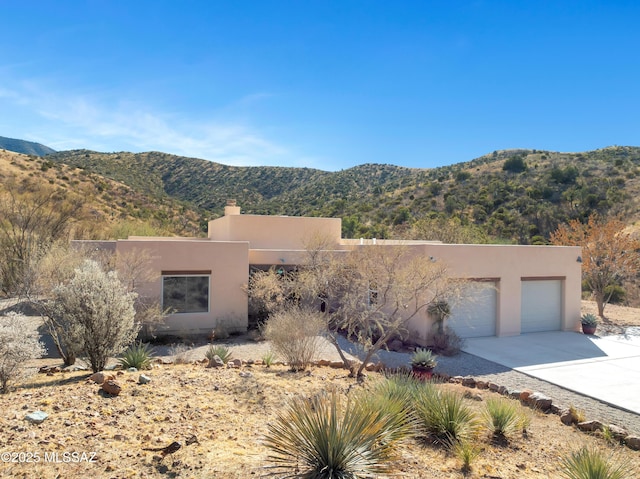 pueblo-style home featuring a garage and a mountain view