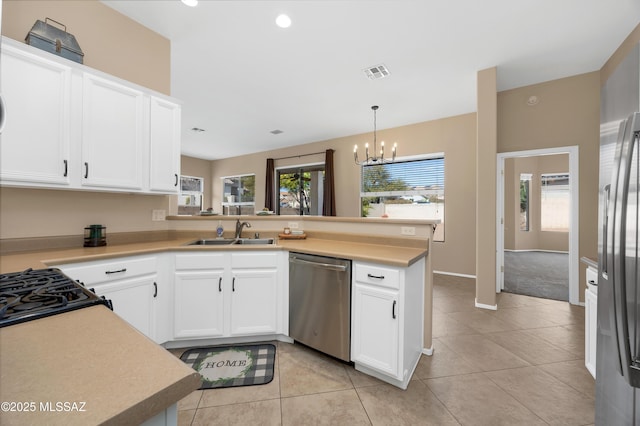 kitchen with sink, appliances with stainless steel finishes, white cabinets, decorative light fixtures, and kitchen peninsula