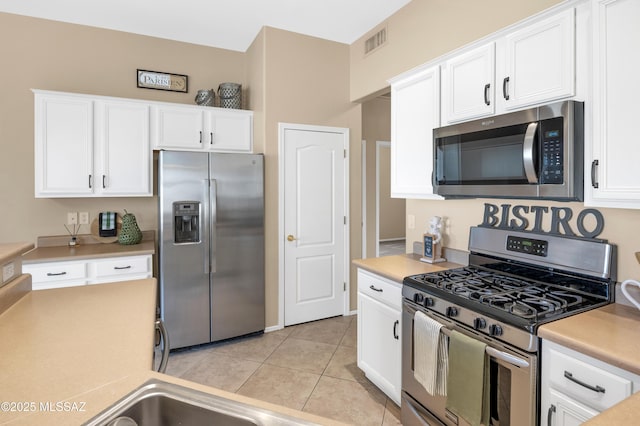 kitchen with appliances with stainless steel finishes, light tile patterned floors, and white cabinets