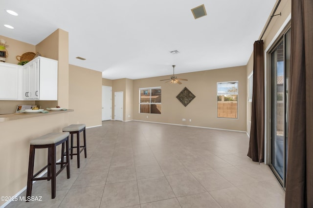 kitchen with white cabinetry, a breakfast bar area, ceiling fan, and light tile patterned floors