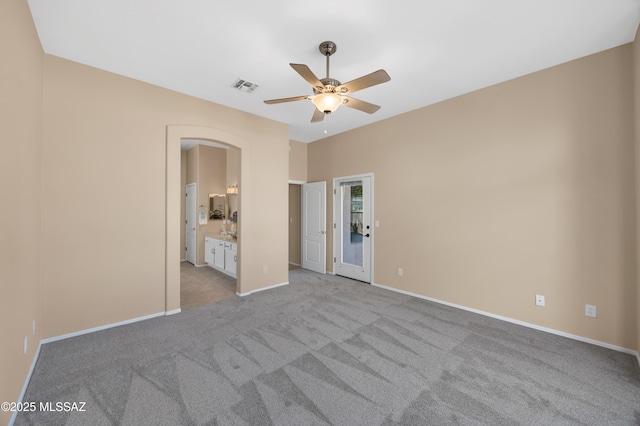 unfurnished bedroom with ensuite bathroom, light colored carpet, and ceiling fan