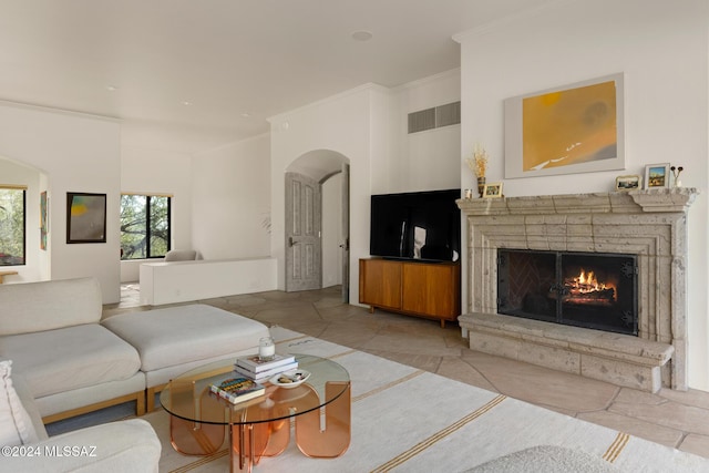 living room with a stone fireplace and ornamental molding