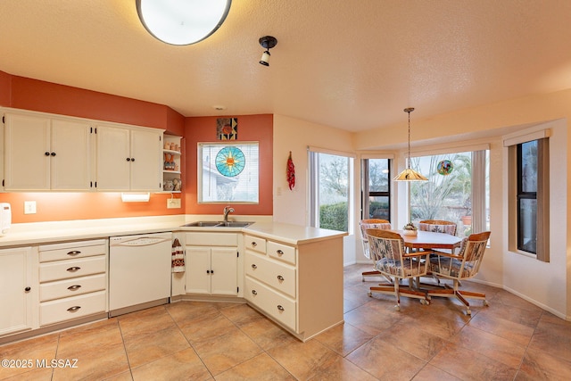 kitchen with sink, white dishwasher, kitchen peninsula, pendant lighting, and white cabinets