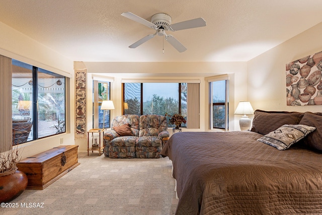 carpeted bedroom featuring ceiling fan, multiple windows, and a textured ceiling