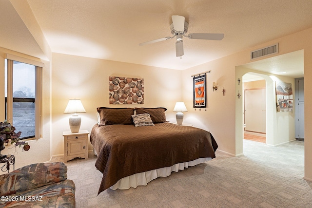 bedroom with light colored carpet, a textured ceiling, and ceiling fan