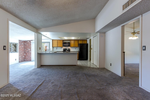 kitchen with lofted ceiling, black appliances, light carpet, decorative backsplash, and kitchen peninsula