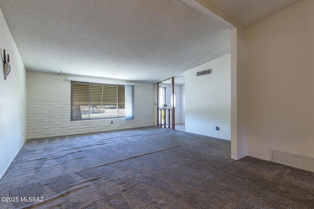 carpeted spare room featuring vaulted ceiling and a textured ceiling