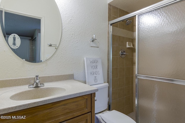 bathroom with a shower with door, vanity, and toilet