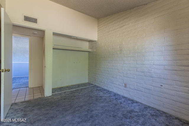 interior space featuring brick wall, carpet, and a textured ceiling