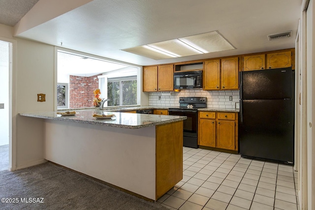 kitchen featuring stone counters, kitchen peninsula, backsplash, and black appliances