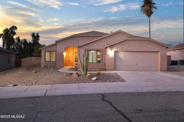 ranch-style home with fence, cooling unit, an attached garage, stucco siding, and concrete driveway