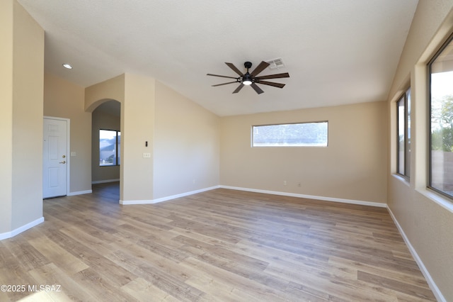 unfurnished room featuring arched walkways, lofted ceiling, ceiling fan, and light wood-style floors