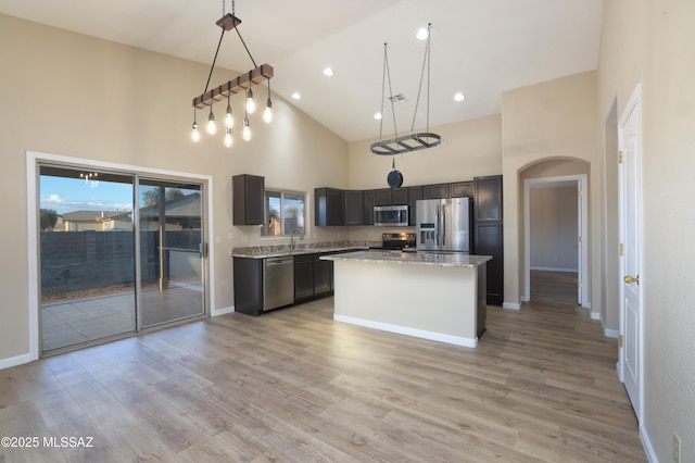 kitchen with appliances with stainless steel finishes, baseboards, a sink, and high vaulted ceiling