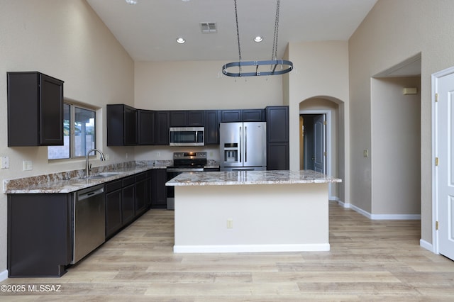 kitchen with a sink, stainless steel appliances, visible vents, arched walkways, and a center island