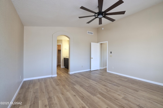 empty room featuring ceiling fan, lofted ceiling, a textured ceiling, and light wood-type flooring