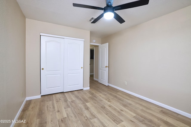 unfurnished bedroom featuring ceiling fan, a textured ceiling, light wood-type flooring, and a closet