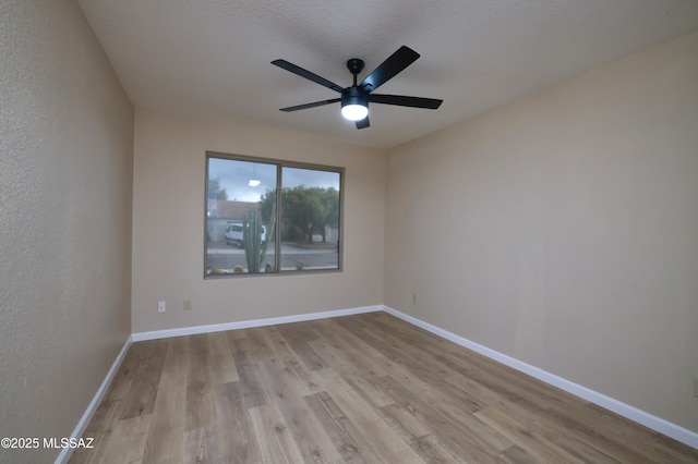 unfurnished room featuring baseboards, a ceiling fan, and wood finished floors