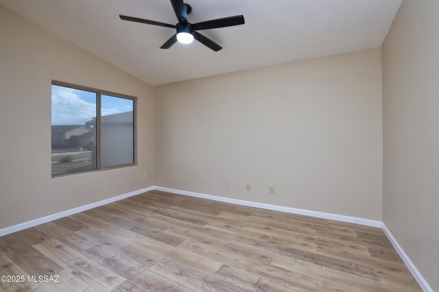 spare room with baseboards, vaulted ceiling, wood finished floors, and a ceiling fan