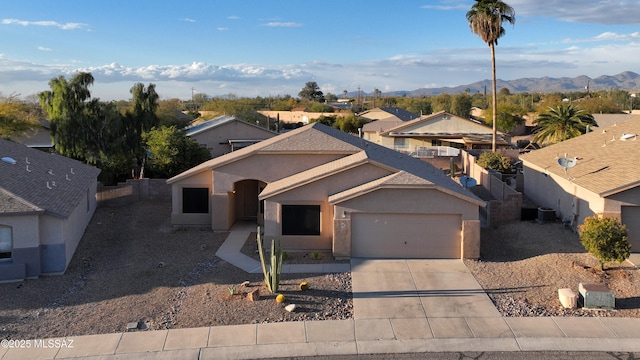 view of front of property featuring concrete driveway, an attached garage, stucco siding, and a mountain view