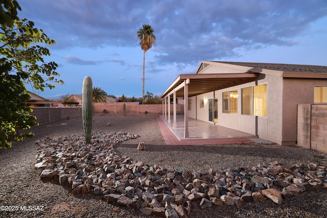 back house at dusk with a patio area