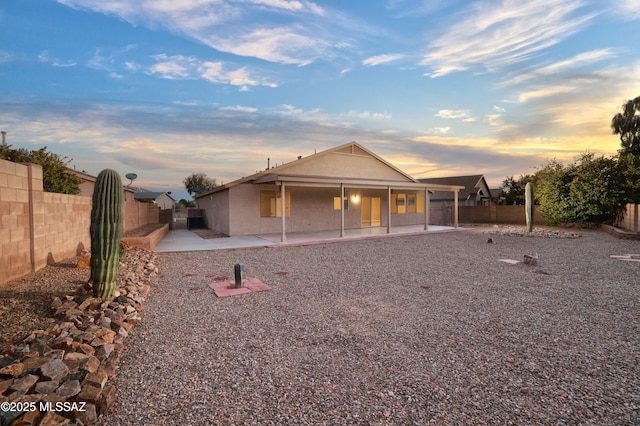 back house at dusk featuring a patio