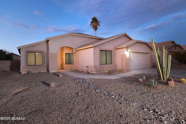 single story home featuring driveway, stucco siding, and an attached garage