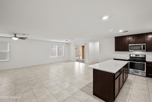 kitchen with light tile patterned flooring, appliances with stainless steel finishes, a center island, and dark brown cabinets