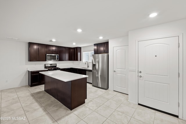 kitchen featuring a kitchen island, appliances with stainless steel finishes, sink, light tile patterned floors, and dark brown cabinets