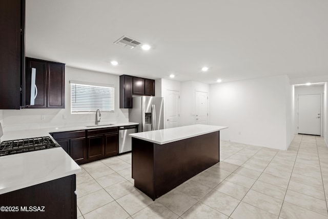 kitchen featuring sink, a center island, dark brown cabinets, light tile patterned floors, and appliances with stainless steel finishes