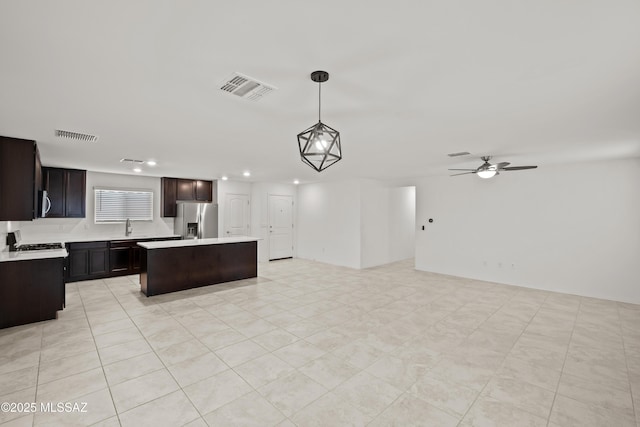 kitchen with sink, stainless steel fridge with ice dispenser, hanging light fixtures, light tile patterned floors, and a kitchen island