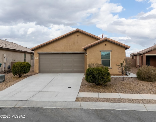 view of front of property with a tiled roof, an attached garage, concrete driveway, and stucco siding