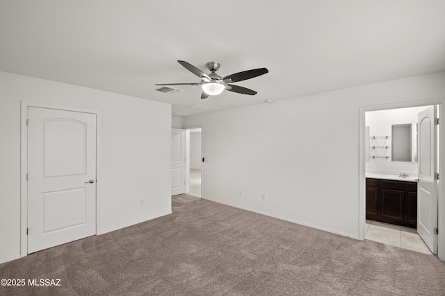 unfurnished bedroom with light carpet, sink, ceiling fan, and ensuite bathroom