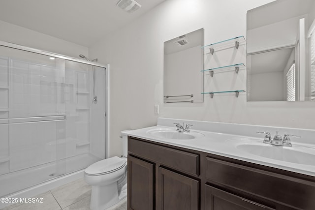 bathroom featuring tile patterned flooring, vanity, a shower with shower door, and toilet