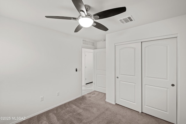 unfurnished bedroom featuring light carpet, a closet, and ceiling fan